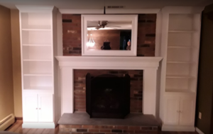 A fire place with white cabinets and shelves on each side.